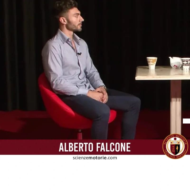 Giovane uomo seduto su poltrona rossa con tavolo, tazza e teiera, fascia bordeaux con nome e logo Scienze Motorie.