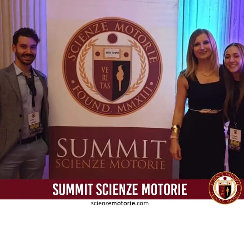 Cinque persone in abbigliamento formale posano accanto a un cartellone con il logo e titolo "Summit Scienze Motorie" durante un evento interno ben illuminato.