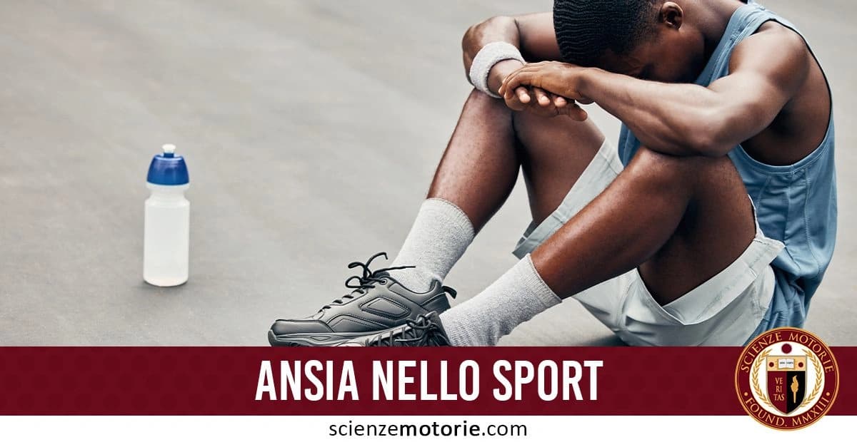 Atleta seduto a terra con la testa appoggiata sulle braccia e le ginocchia sollevate, indossa abbigliamento sportivo e scarpe da ginnastica. Accanto a lui una bottiglia d'acqua. In basso, testo 'ANSIA NELLO SPORT' e il logo di ScienzeMotorie.com
