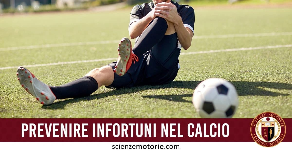 Calciatore seduto sul campo da calcio mentre tiene la gamba con entrambe le mani, probabilmente a causa di un infortunio. Un pallone è posizionato davanti a lui. Testo in basso: "Prevenire infortuni nel calcio" accompagnato dal logo Scienze Motorie.com.
