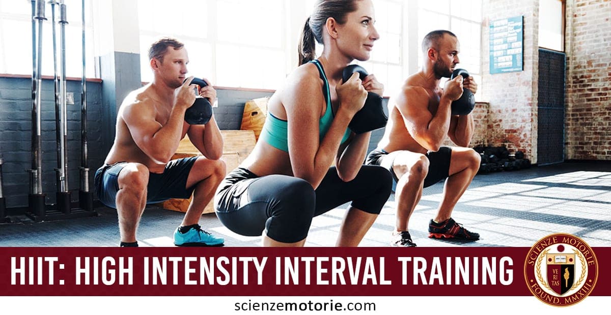 Tre persone eseguono squat con pesi durante un allenamento HIIT in palestra, indossando abbigliamento sportivo, con attrezzatura sullo sfondo.