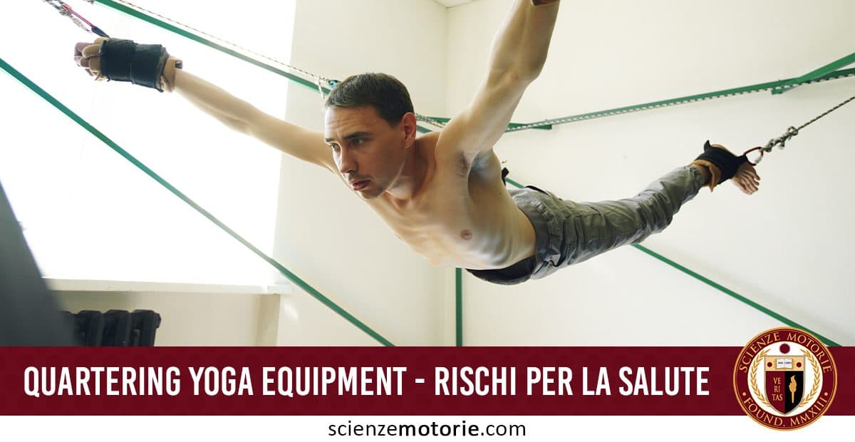 Uomo a torso nudo sospeso in aria con braccia e gambe divaricate, sostenuto da cinghie per yoga in una stanza, con testo che segnala rischi per la salute dell’attrezzatura.