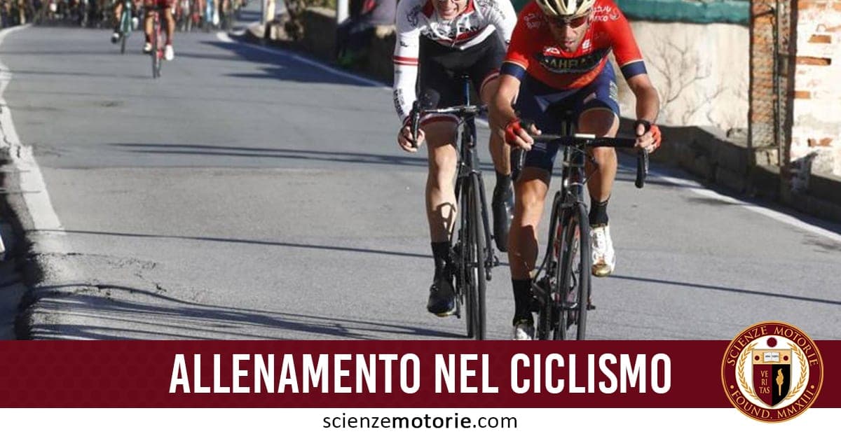 Due ciclisti in abbigliamento tecnico pedalano su una strada asfaltata durante un allenamento, con altri ciclisti sullo sfondo e il testo "Allenamento nel ciclismo" in sovrimpressione.
