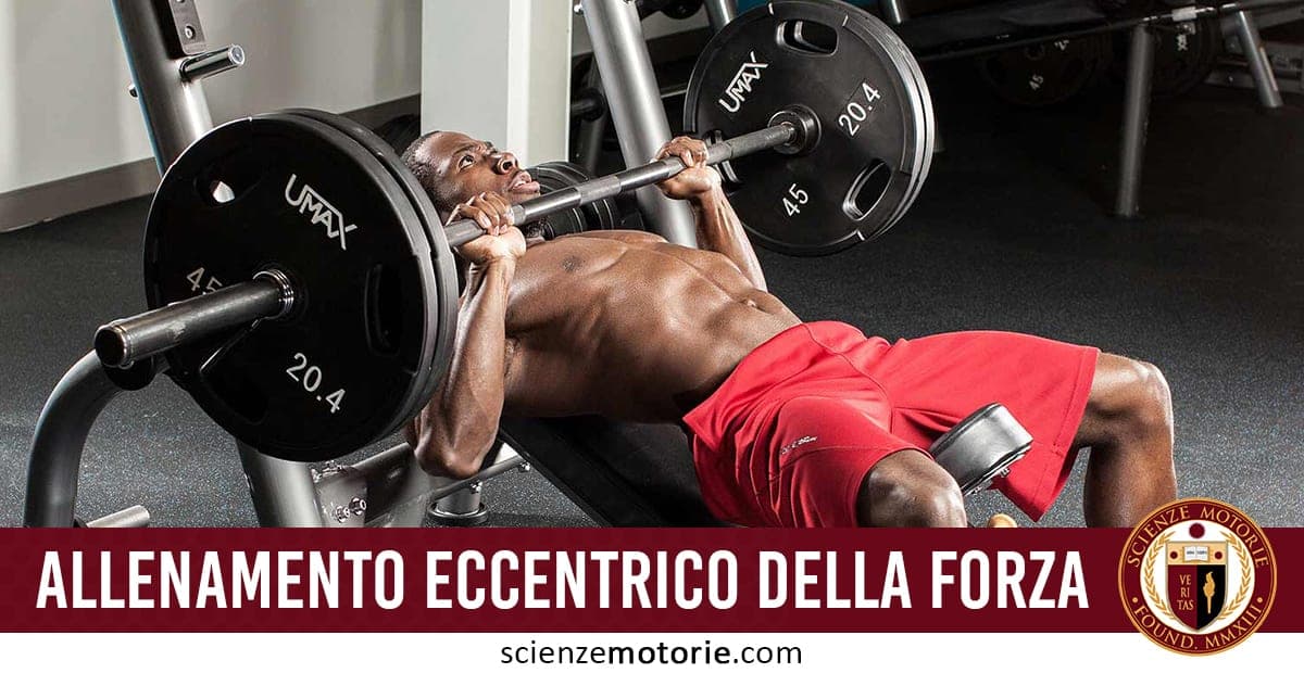 Uomo che esegue un esercizio di sollevamento pesi su panca inclinata con bilanciere, indossa pantaloncini rossi; in basso, il testo "Allenamento eccentrico della forza" e il logo di Scienze Motorie.