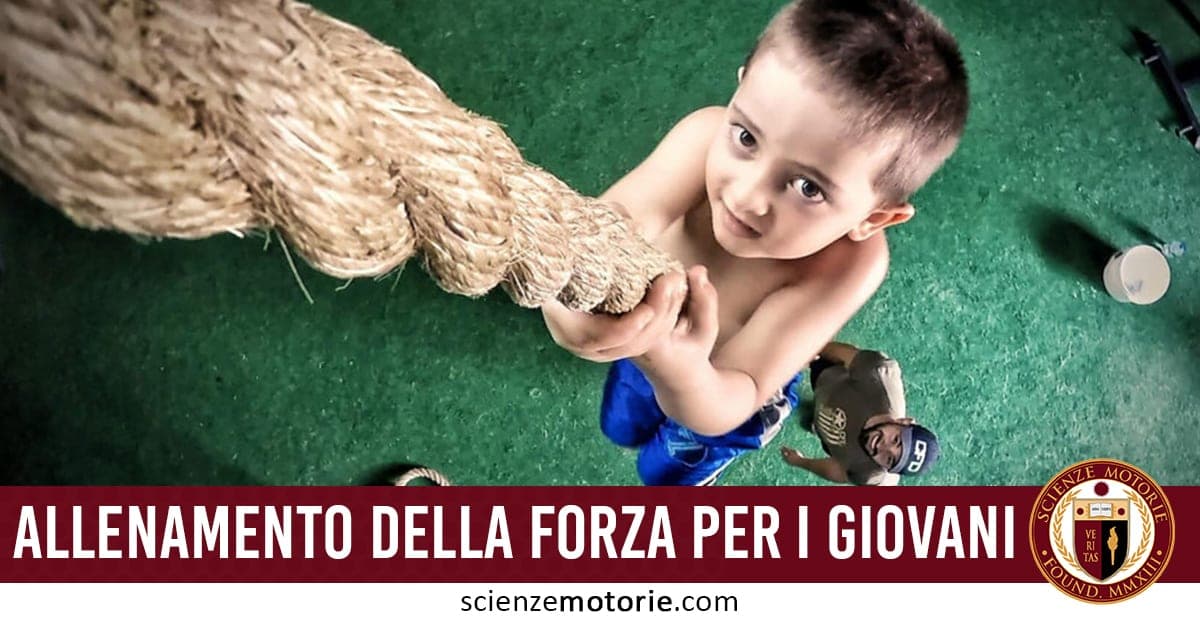 Giovane ragazzo impegnato nell’arrampicata su corda durante una sessione di allenamento in palestra, assistito da un istruttore.