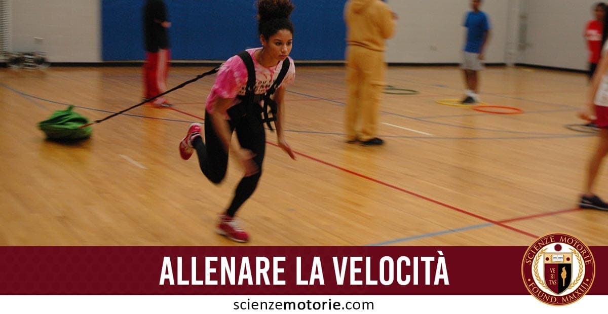 Persona in palestra che corre indossando un’imbracatura con peso, circondata da cerchi colorati sul pavimento; testo “ALLENARE LA VELOCITÀ” e logo di scienze motorie.