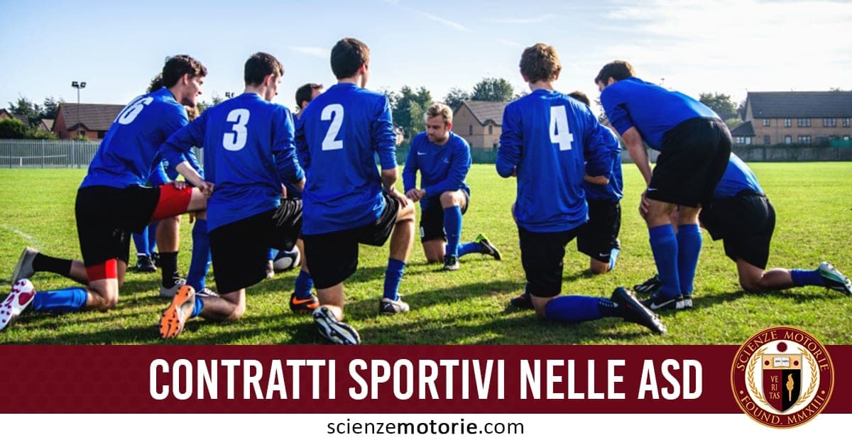 Gruppo di calciatori in maglie blu e pantaloncini neri in cerchio sul campo durante una riunione tecnica. In basso è presente il logo di ScienzeMotorie.com.