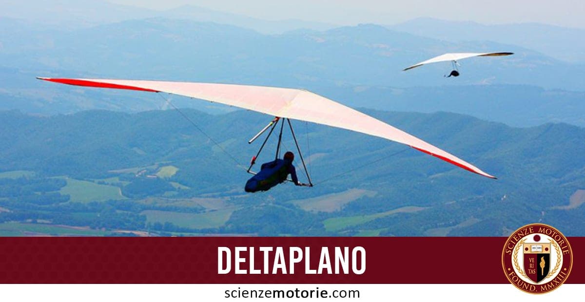 Due deltaplani in volo sopra un paesaggio collinare verde e montuoso, con pilota visibile sotto l’ala rossa.