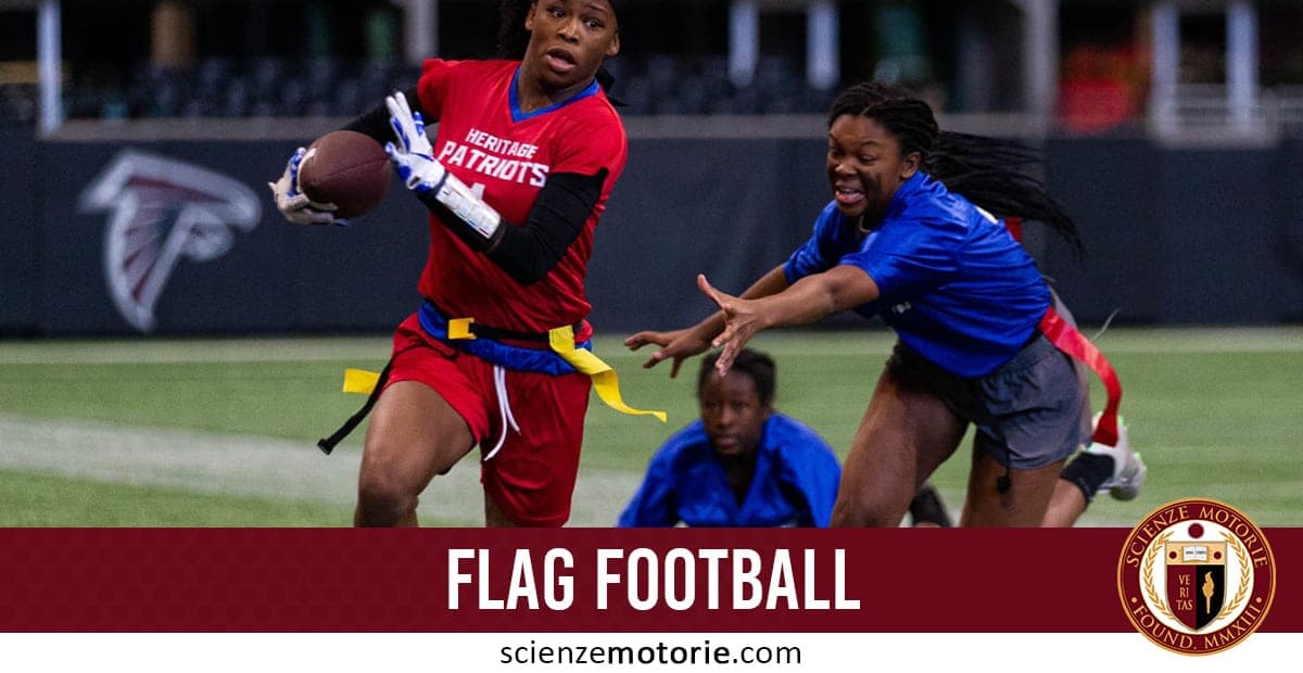 Due giocatrici in azione durante una partita di flag football, una in divisa rossa con palla e l’altra in divisa blu che cerca di strappare la bandiera.