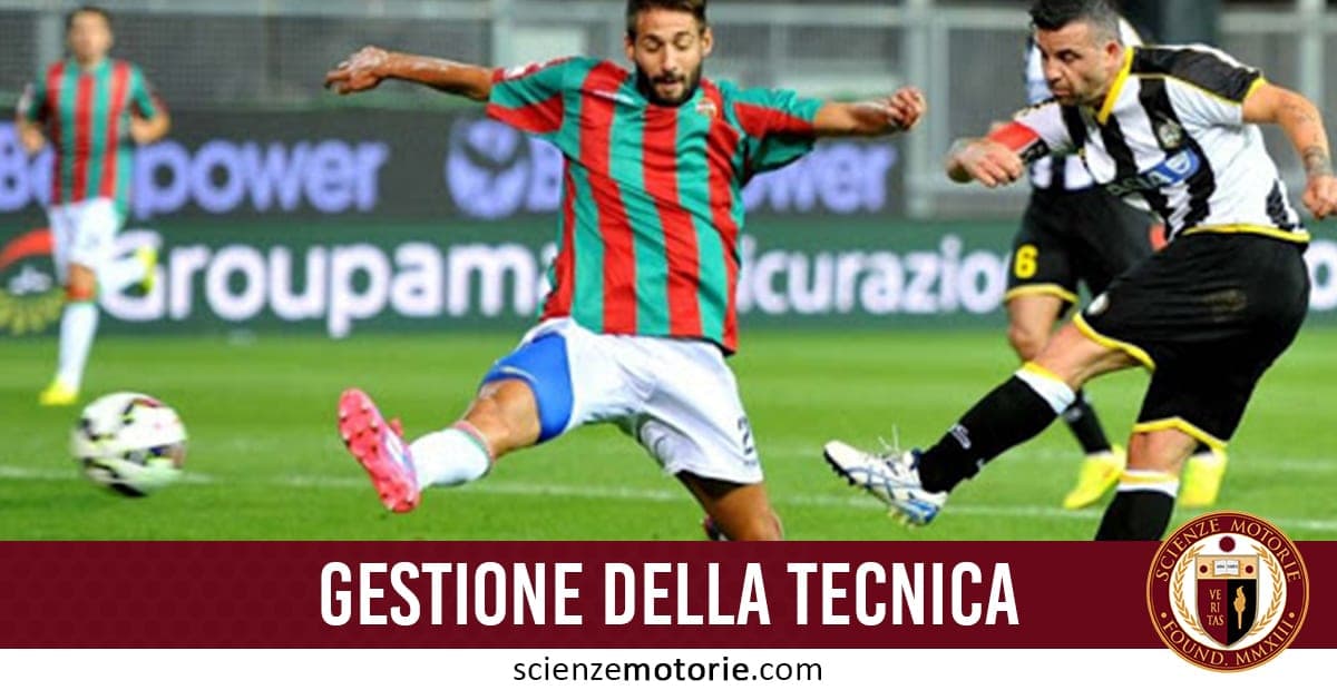 Due calciatori in azione su un campo da calcio: uno in maglia rossa e verde calcia la palla, l’altro in bianco e nero cerca di contrastarlo.