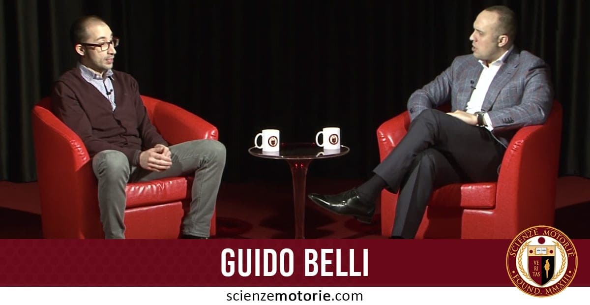Due uomini seduti su poltrone rosse conversano davanti a un tavolino con tazze. Sullo sfondo c’è una tenda scura; in basso il nome "Guido Belli" e il logo "Scienze Motorie".