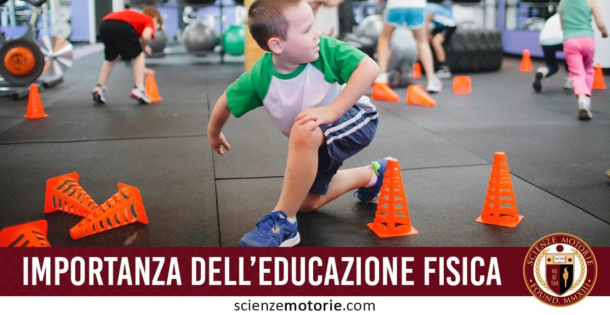 Bambini che corrono intorno a coni arancioni in palestra, con un bambino in maglietta verde e pantaloncini blu in primo piano. Testo "Importanza dell'educazione fisica" e logo scienzemotorie.com.