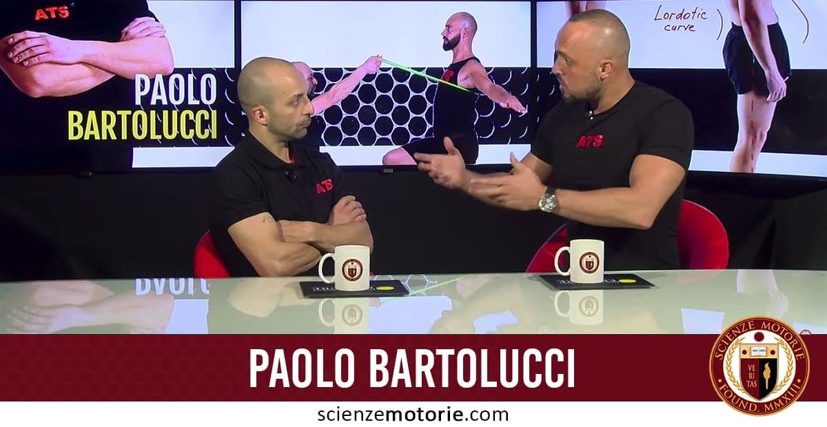 Due persone con magliette ATS sedute a un tavolo con tazze e documenti, davanti a uno schermo che mostra esercizi fisici e il nome Paolo Bartolucci.