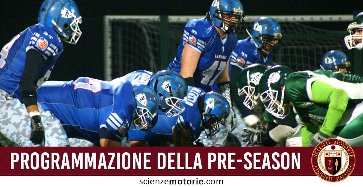 Squadre di football americano in divise blu e verde schierate per una giocata, con caschi e protezioni.