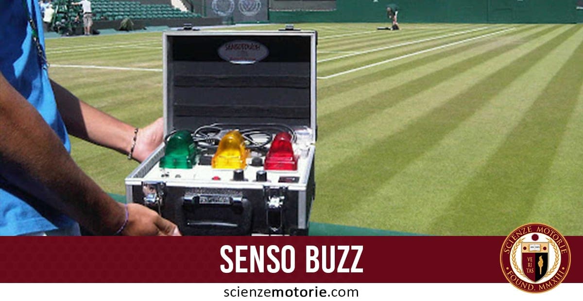 Persona che tiene una valigetta aperta con sensori colorati verde, giallo e rosso, davanti a un campo da tennis in erba ben curato con linee bianche e operatori al lavoro sullo sfondo.