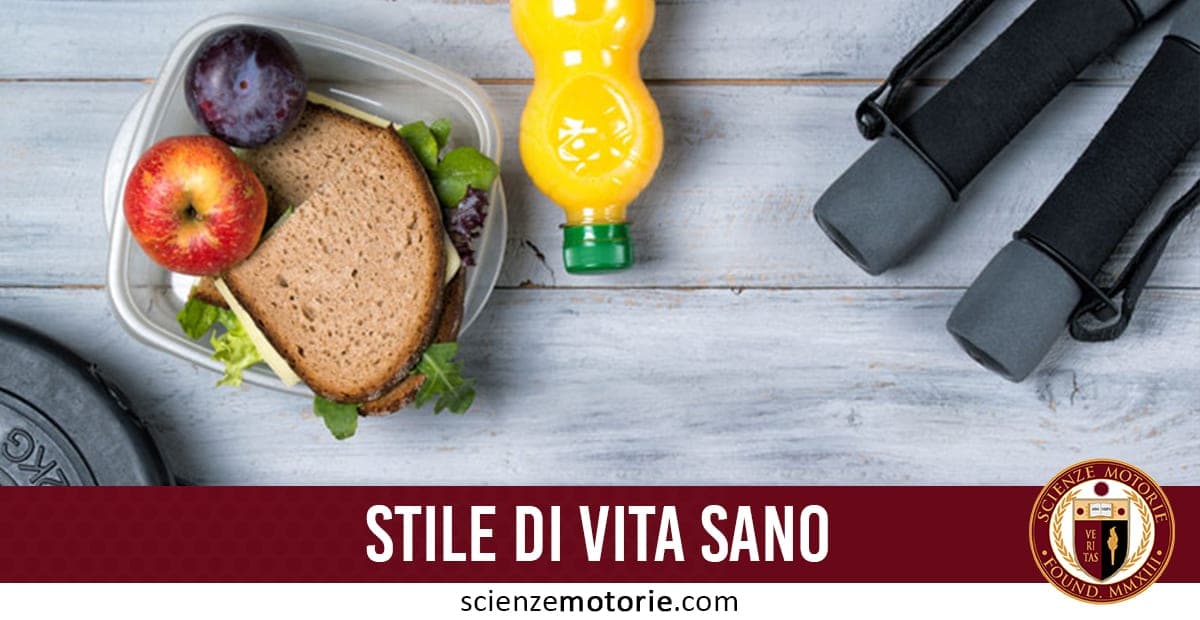 Contenitore per il pranzo con panino, mela e prugna accanto a una bottiglia gialla e manubri da allenamento; in basso testo “STILE DI VITA SANO” e logo ScienzeMotorie.com.