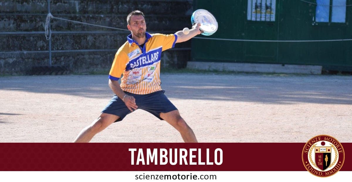 Uomo concentrato che gioca a tamburello su un campo all’aperto, indossa maglia colorata e pantaloncini.