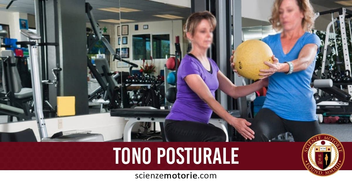 Due persone in palestra eseguono un esercizio con la palla medica. Una guida l’altra. Sullo sfondo attrezzature ginniche e uno specchio. In basso, la scritta “TONO POSTURALE” e il logo Scienze Motorie.