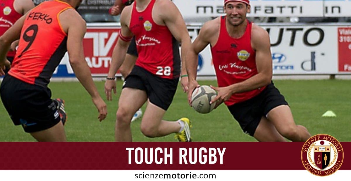 Giocatori di touch rugby in campo, uno con canotta rossa che tiene la palla ovale, con pubblicità sullo sfondo.