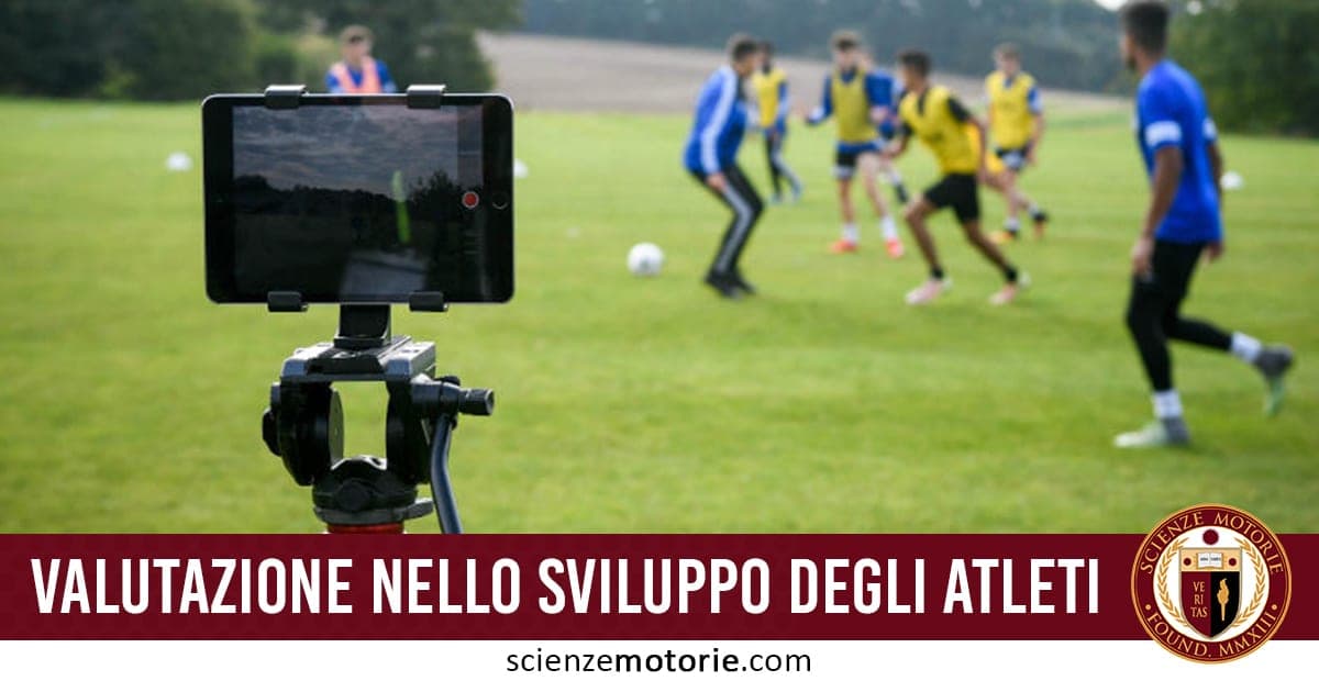 Campo di calcio con giocatori in allenamento, alcuni con pettorine gialle e altri con maglie blu, e dispositivo su treppiede che registra, con testo "Valutazione nello sviluppo degli atleti" e logo Scienze Motorie.