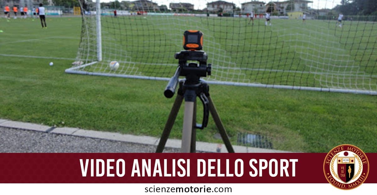Telecamera su treppiede davanti alla porta di calcio durante una partita, con giocatori in azione sul campo.